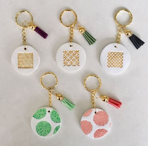 Five air dry clay keychains. Each one is round with a different design. 